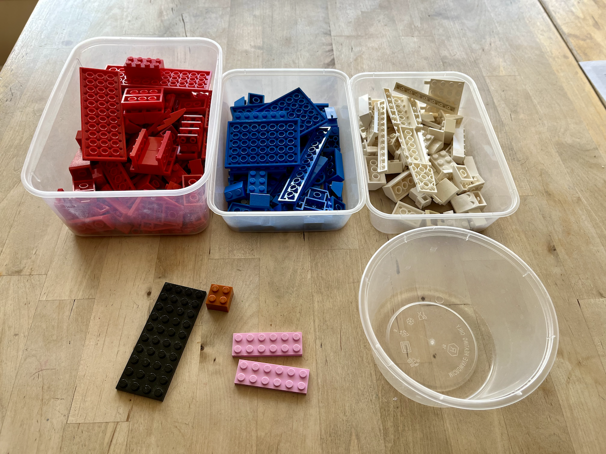 A table with some Lego parts in different boxes